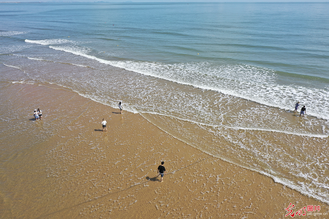 2020年9月29日,游人在金黄色的沙滩上享受海浪的拍打