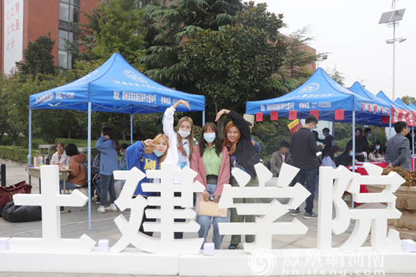 土木工程专业新生王妍与志愿者在学院立体字前合影