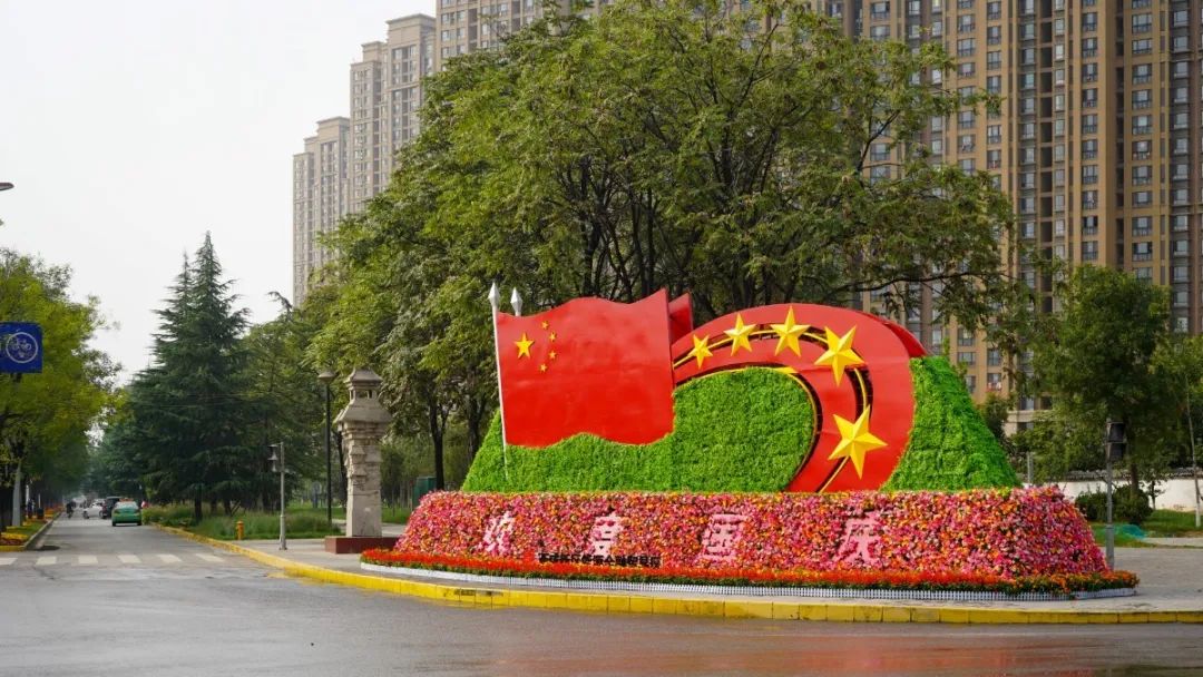 路口整齐摆放着色彩斑斓,造型各异的主题绿雕,为