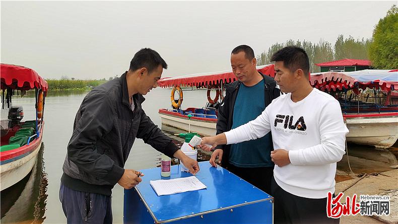 10月1日，张平均（右一）正在赵北口镇南街村旅游码头值勤，给每个游客量体温、查看健康码、登记个人信息。 河北日报记者原付川摄