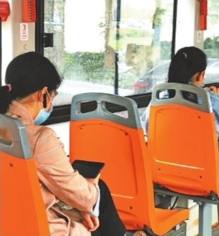 575路公交车上，乘客使用蓝牙耳机看剧，手机屏幕亮度也调得很低。