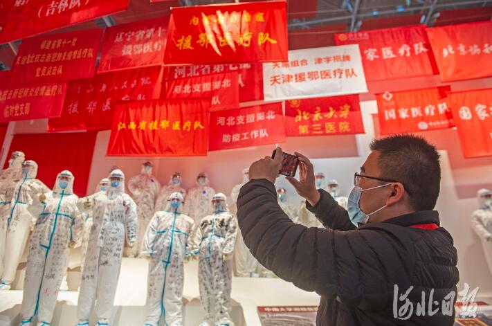 参展中，赵明拿起手机拍下“河北省支援湖北医疗队”“河北省第七批支援湖北医疗队”等4面队旗。 河北日报记者田明摄
