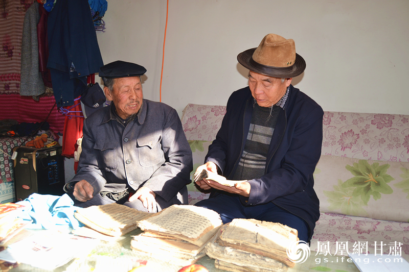吕兰生（左）展示他所保存的皮影戏剧本 杨文远 摄
