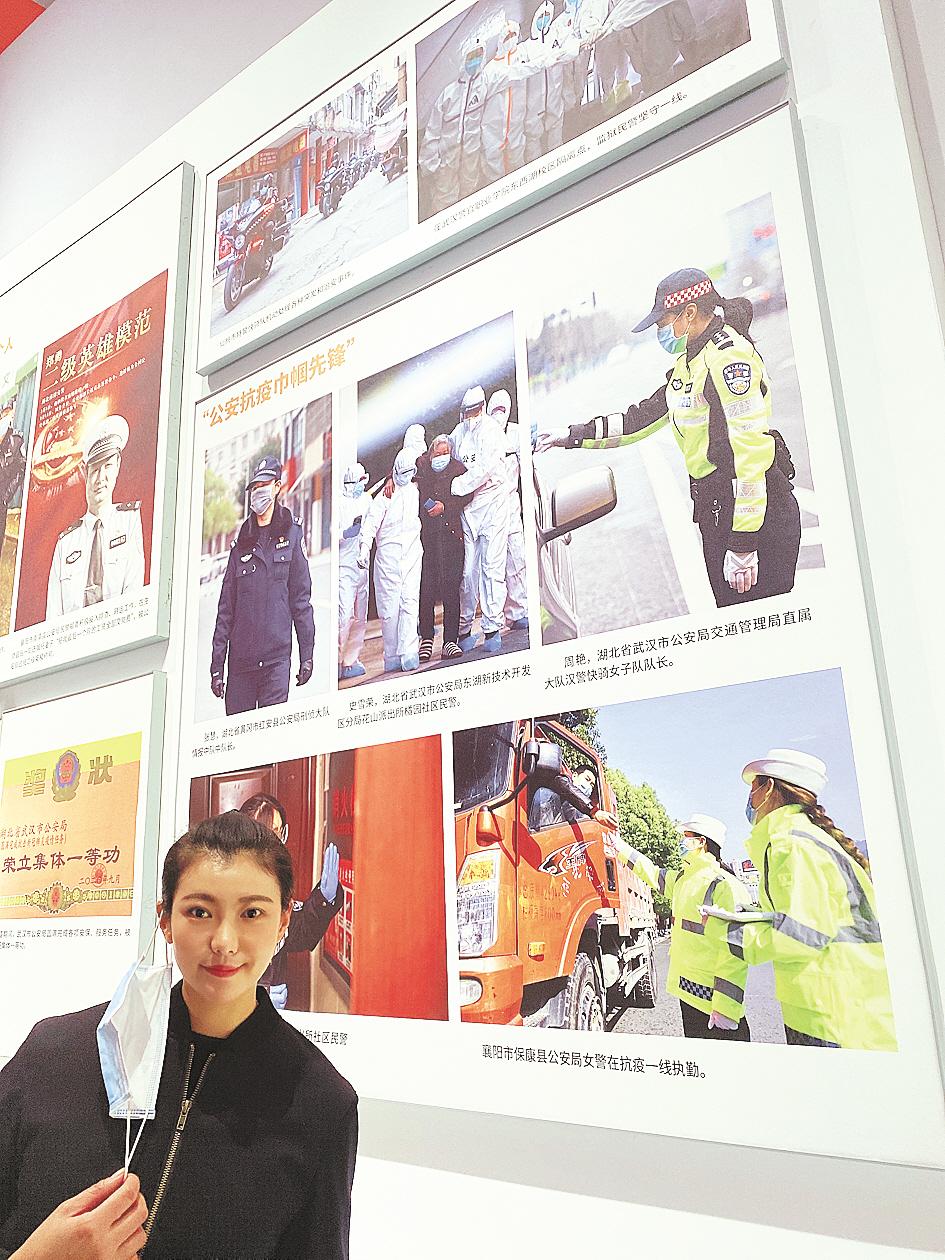 周艳在自己的照片(右上)前留影。