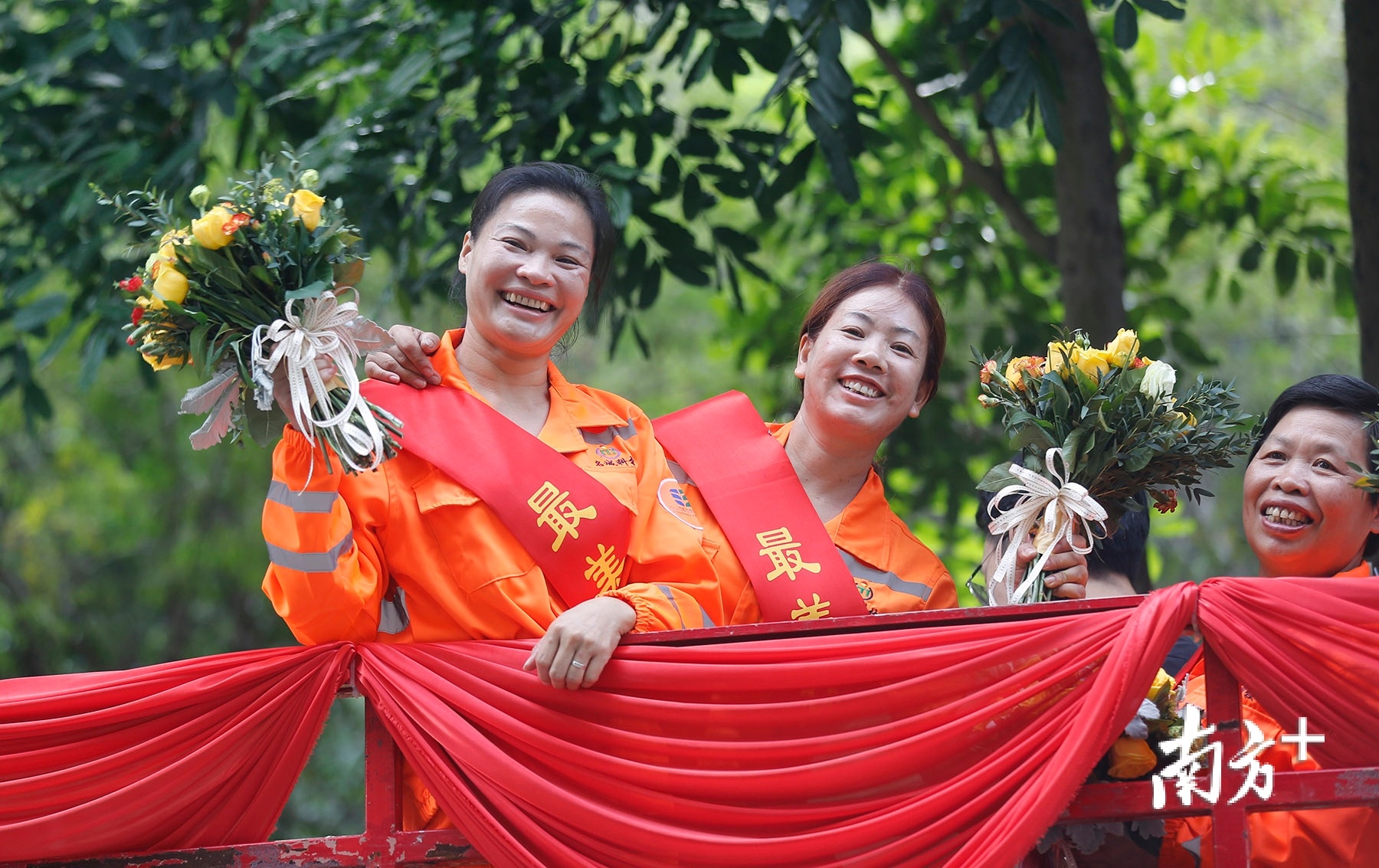 坐在巡游车上的环卫工人喜笑颜开.