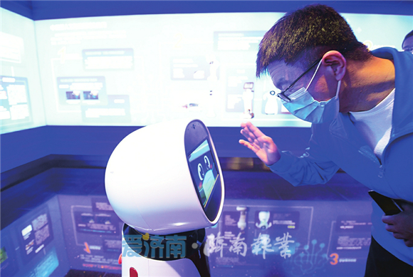记者们与先行区中科新经济产业园中的智能机器人互动。