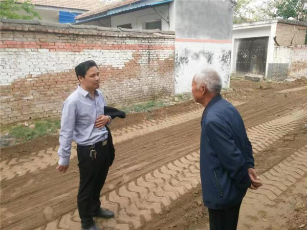 秦景华（左）看村里修路状况