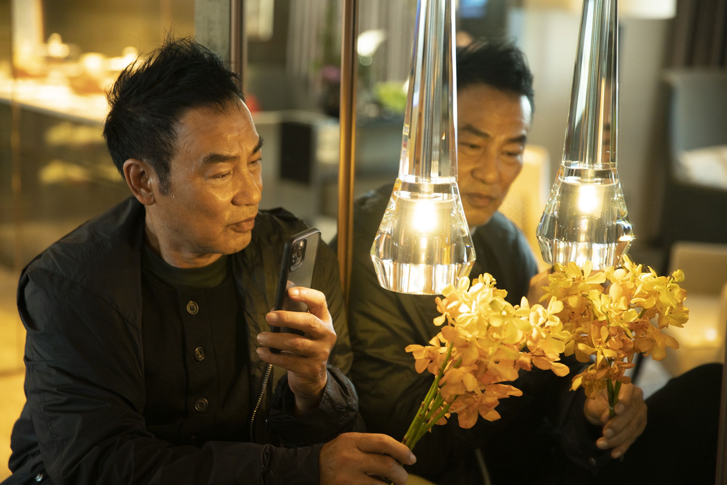 采访现场，任达华借着灯光，用手机拍下一束花。新京报记者 郭延冰 摄
