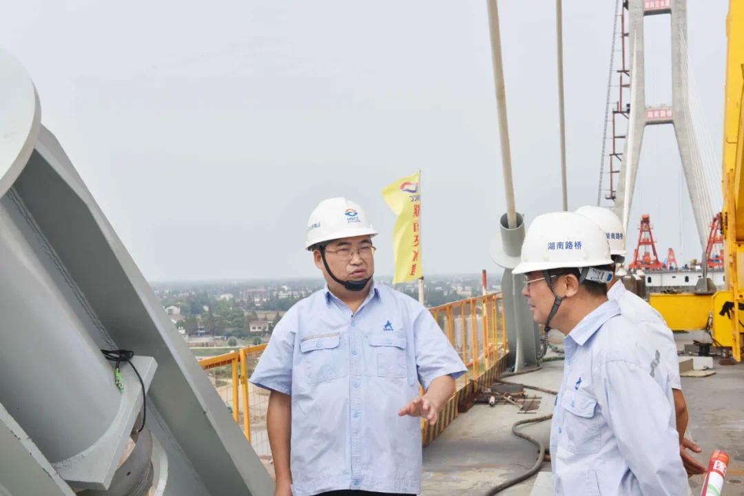 ▲2018年8月，方联民（左）在湖南最大跨径斜拉桥南洞庭大桥与现场技术员探讨梁段吊装问题