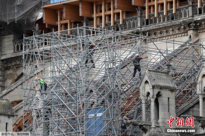 资料图：当地时间2020年6月17日，法国巴黎，工人拆除巴黎圣母院被烧毁的脚手架，并安装新的脚手架。