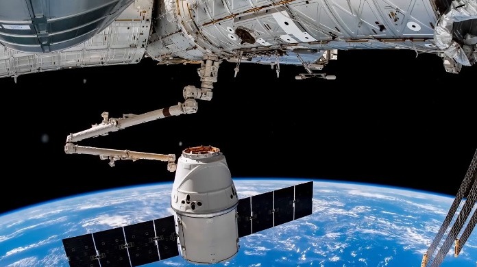 SpaceX龙飞船的机械臂与蓝色背景的地球