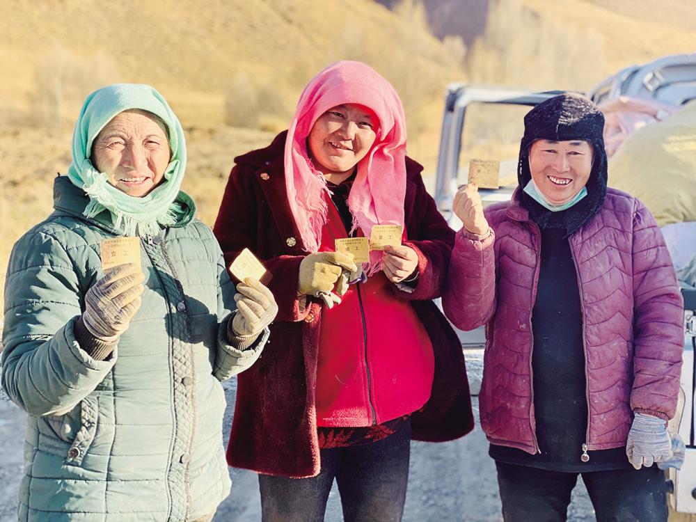 在中藏药材种植基地,村民们领到一天的工票很开心.