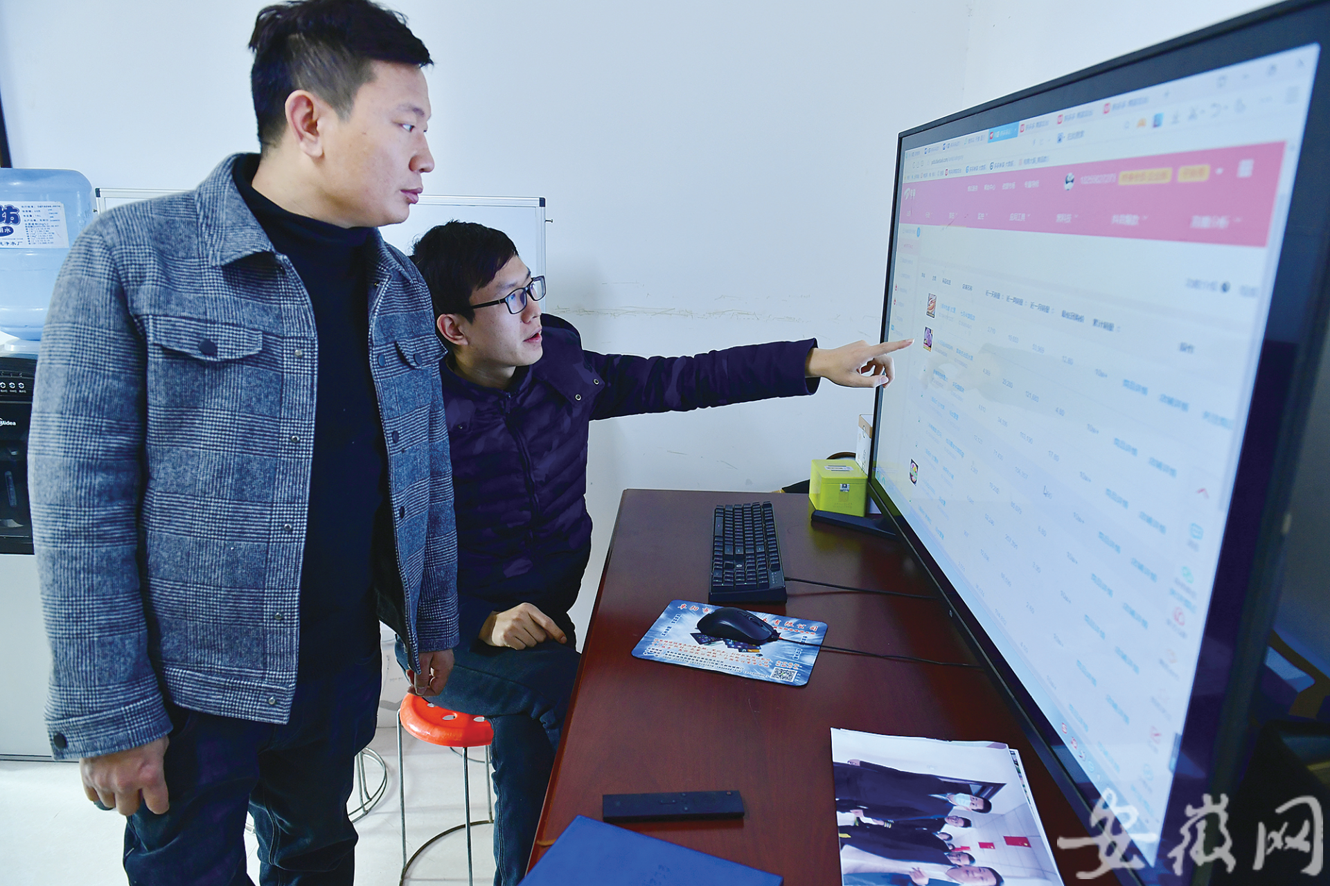 杨道林（左）在办公室里查看各个网店的销售数据。