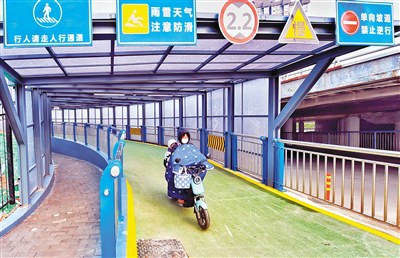 该辅道分设人行梯道与非机动车通道,以降低行人与非机动车道混行的安全风险,并在现场设置交通警示标识。 (首席记者 王健 摄)