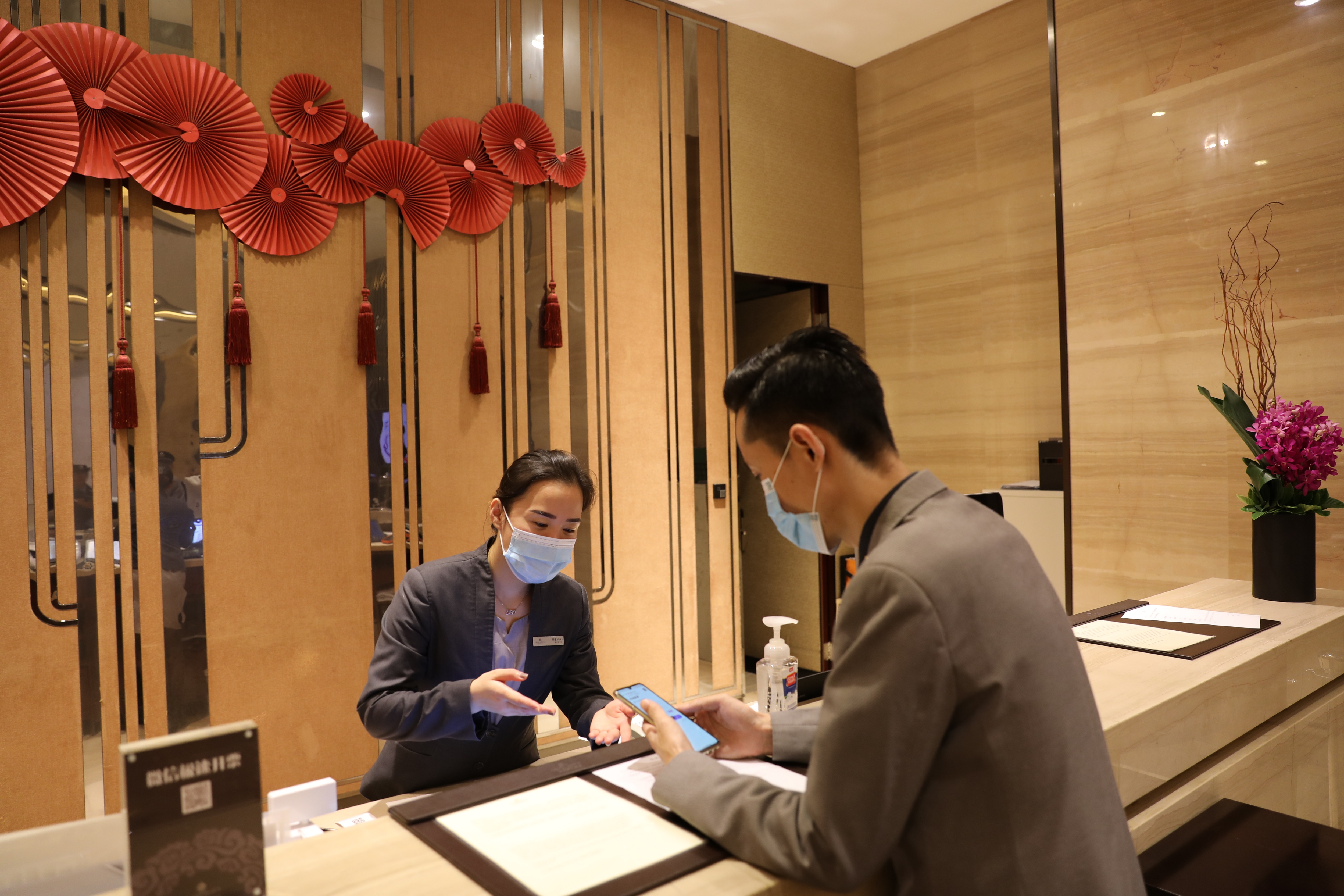 旅店前台工作人员指导群众使用电子身份证登记