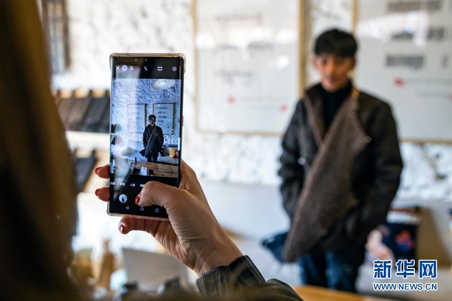 在理塘县勒通古镇的仓央嘉措微型博物馆，一名从外地赶来的粉丝用手机给丁真拍照（12月3日摄）。这里将是丁真未来的工作场所之一。