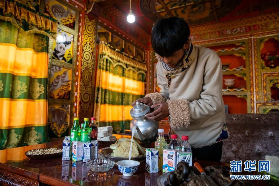 回到位于理塘县格聂雪山下的家里，丁真为客人们倒酥油茶（12月2日摄）。