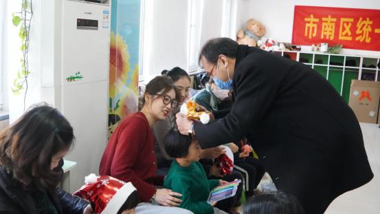 市南区统战部常务副部长杨明强为孩子戴上圣诞帽