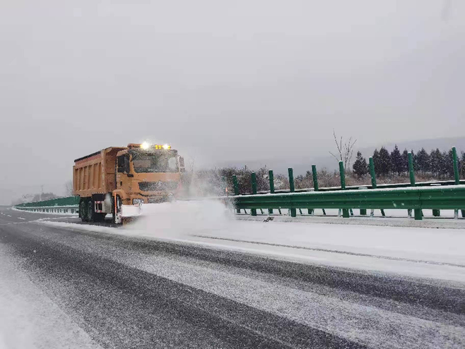 12月25日,除雪车在高速公路上除雪保畅.