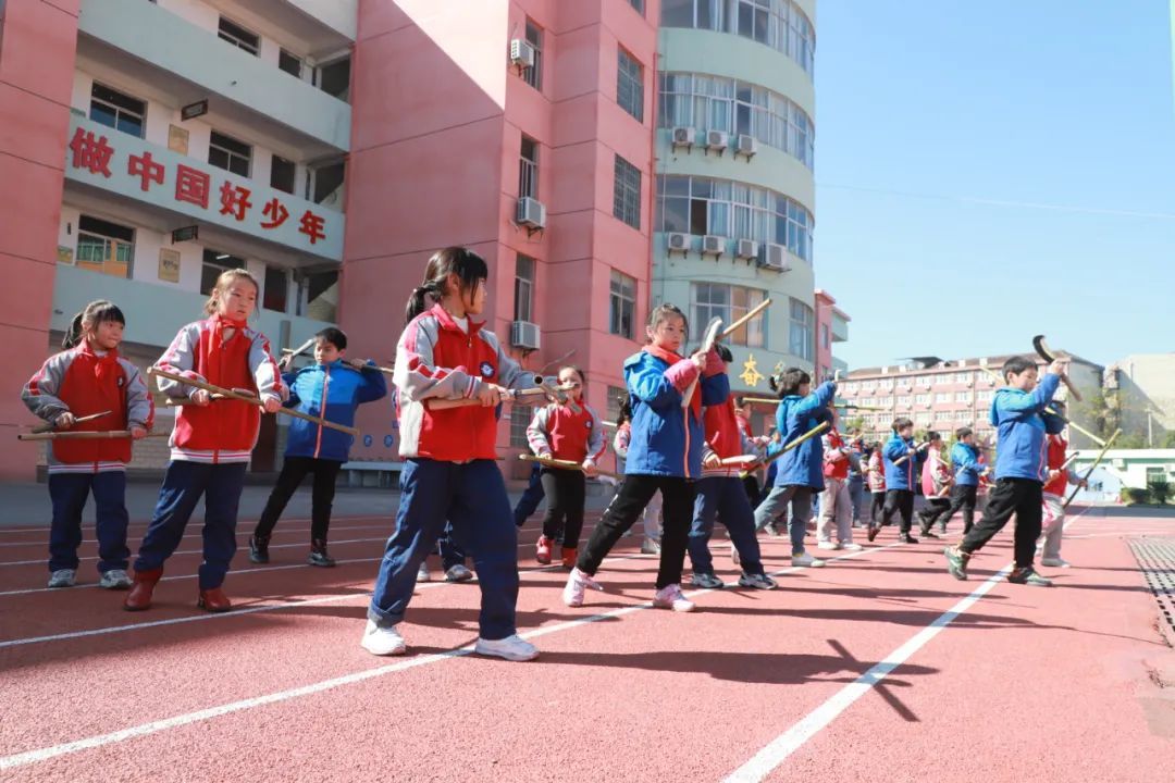 ▲图为宜黄县凤冈一小校园里，学生们在辅导老师的指导下，开展禾杠舞基本功练习活动。