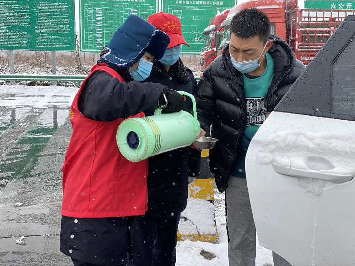12月25日，高速公路工作人员为受困司机送上热水。