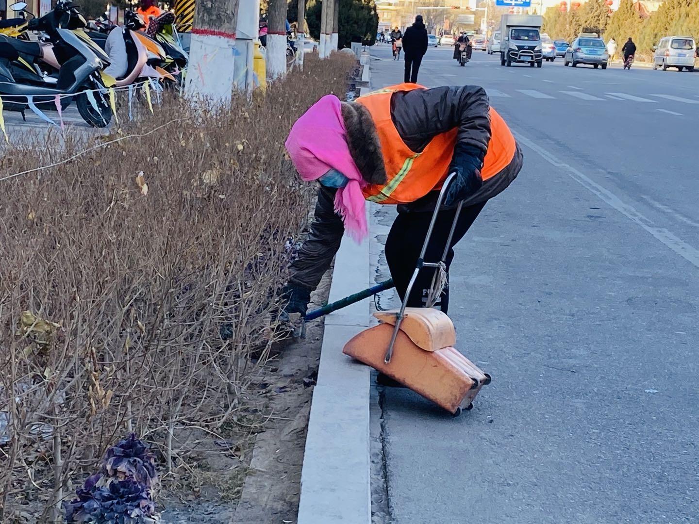 环卫工人正在捡拾树槽中的垃圾 李异炳 摄