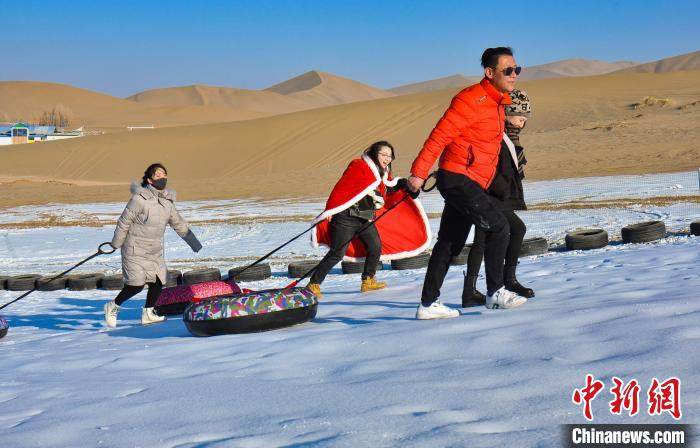 图为游客和市民在鸣沙山下享受大漠冰雪带来的欢乐。　王斌银 摄