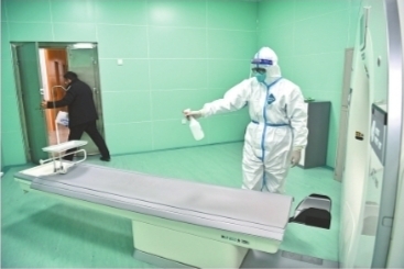 1月12日，武汉市中心医院（后湖院区）发热门诊，身穿防护服的医护人员为患者做完CT检查后，立刻进行消毒处理。记者苗剑 摄