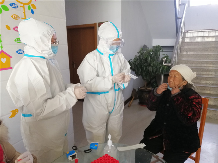 1月12日，志愿者刘亚静（左一）在河北广宗县刘全寨村为老人讲解核酸采样后居家隔离注意事项。