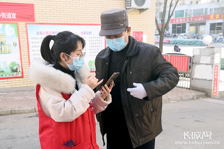 党员志愿者在教群众用手机查看核酸检测情况。