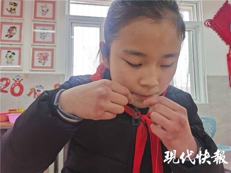△莹莹一手拿针，用嘴唇和牙齿穿针引线