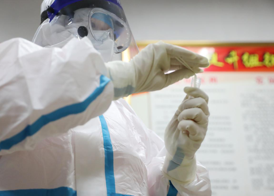 在固安县宫村镇公议存党支部会议室，医护工作者正对核酸检测的村民进行取样。