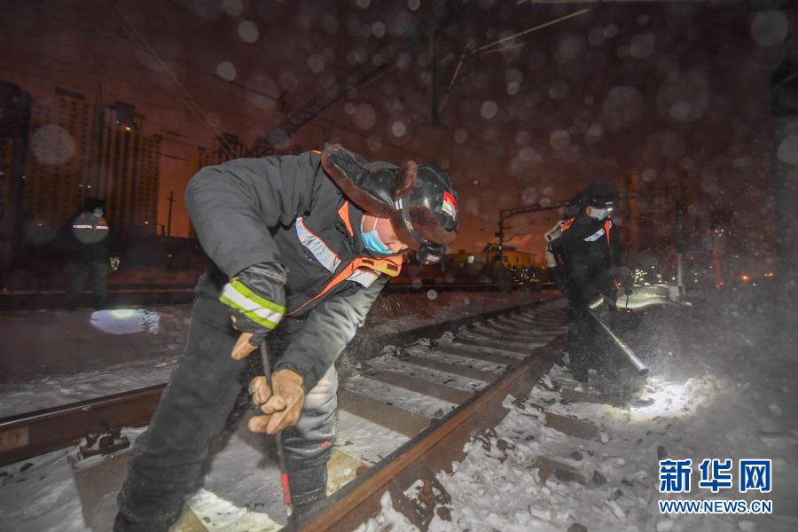 2月5日，在长春火车站，线路工张帅（右）、苏杰为轨道除雪。新华社记者 张楠 摄