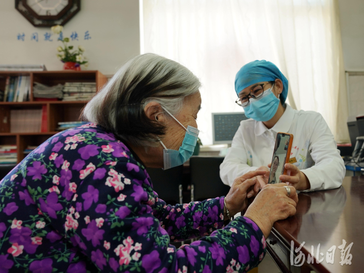 2021年2月10日，在河北省邢台市巨鹿县福缘居医养中心，护工在指导秦民英老人（左）使用微信和家人视频通话。