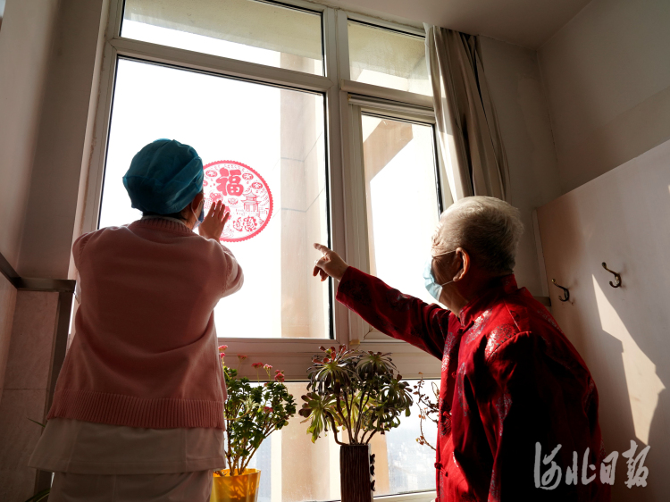 2021年2月10日，在河北省邢台市巨鹿县福缘居医养中心，护工为师英灿老人张贴福字。