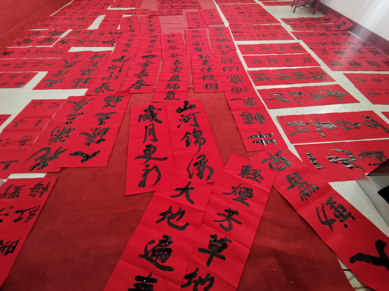 图为书法家们新写的春联铺满了地面活动现场,书法家们运笔如飞,大显身