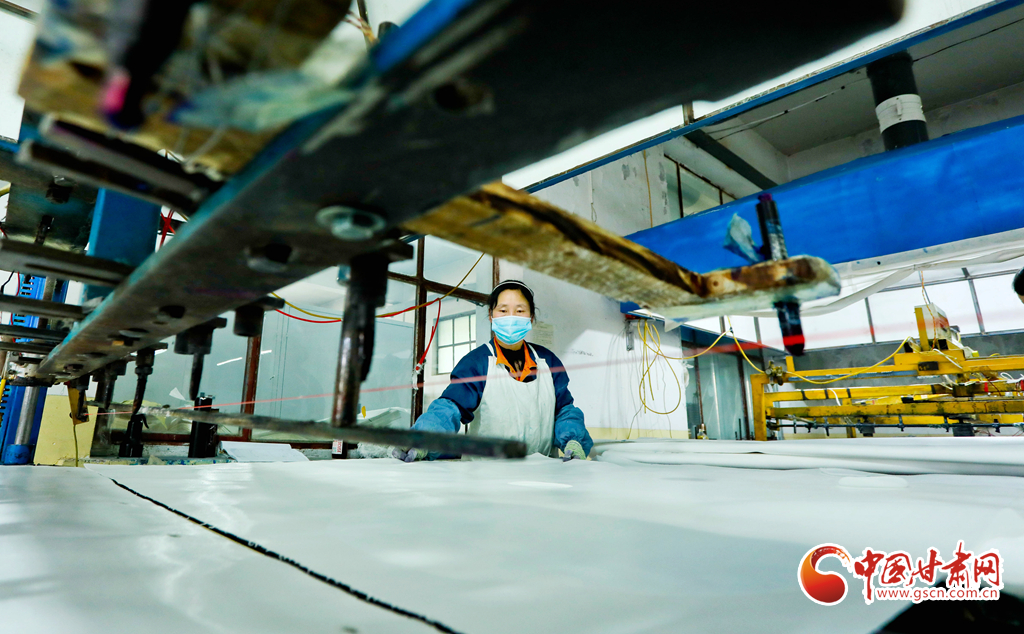 2021年2月22日，甘肃张掖一纺织品公司织布车间内工人们正在紧张有序地进行产业用纺织品裁剪。