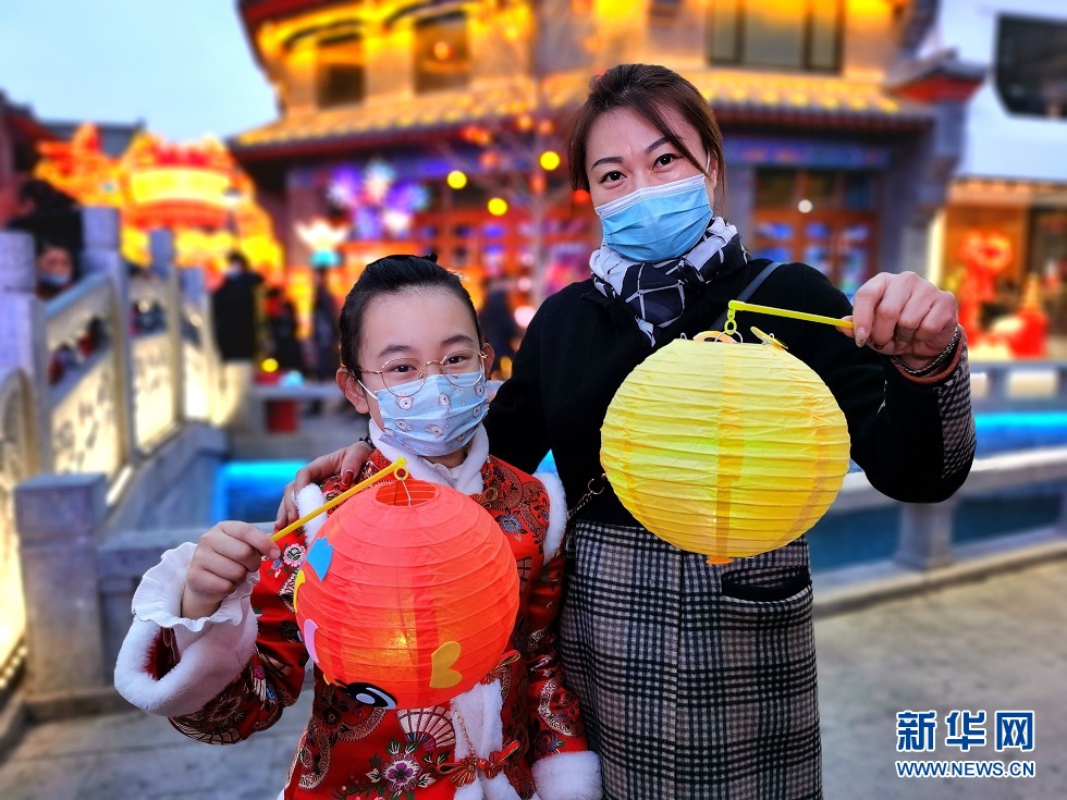 2月25日,一对母女手提精致的花灯在兰州老街逛灯会。新华网发(宋昱静 摄)