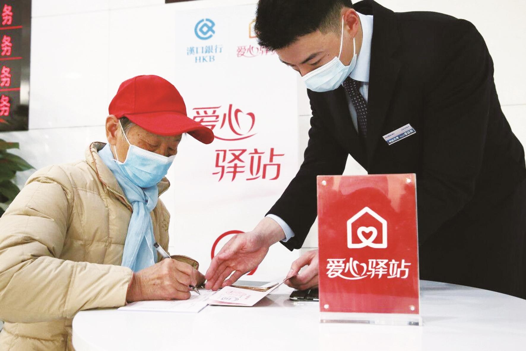 汉口银行营业部工作人员在爱心驿站为老人提供指导填单和使用存折存取钱服务。
