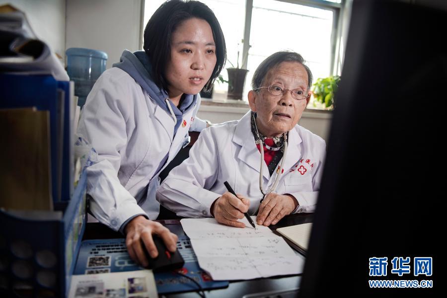 路生梅（右）与佳县中医院儿科医生高苗苗一起探讨患者病情（2020年4月8日摄）。路生梅坚持传、帮、带年轻人，传授自己的医术。新华社记者 陶明 摄
