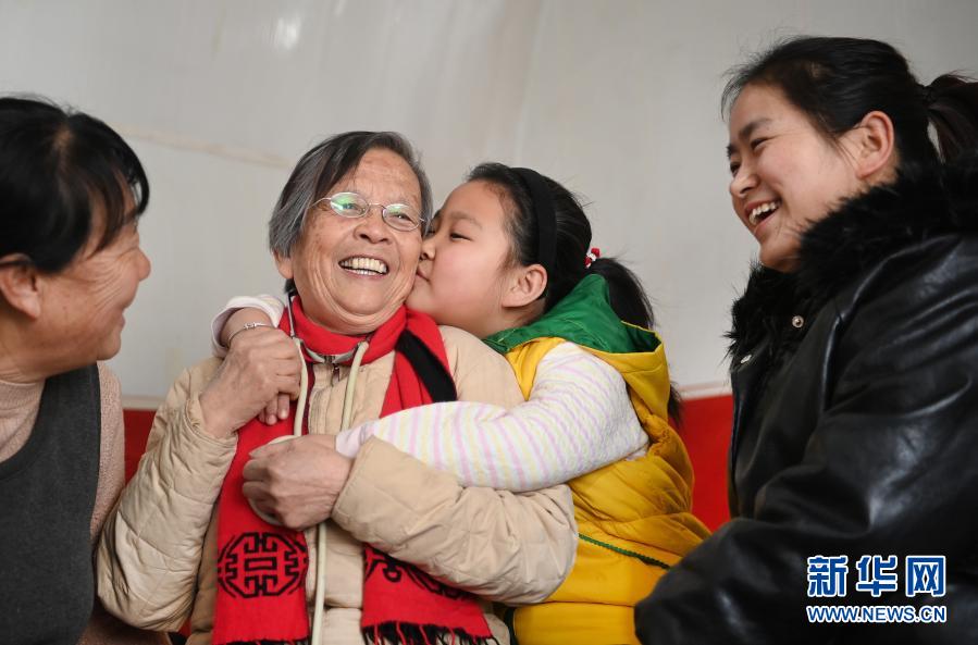 路生梅（左二）在佳县佳州街道凌云社区义诊时，8岁的张宇旋亲密拥抱她（1月17日摄）。张宇㫌的妈妈（右一）、奶奶（左一）都曾让路生梅看过病。新华社记者 陶明 摄