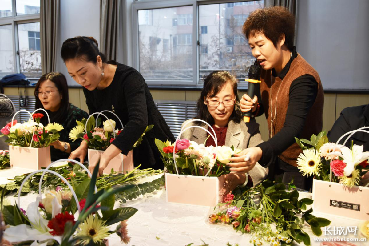 3月5日,花艺师（右一）在查看女职工插花作品。