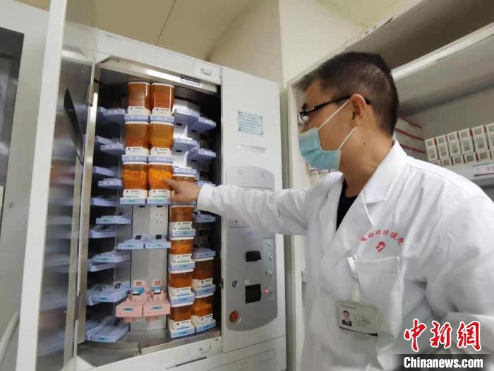 图为在住院部药房工作8年时间的主管药剂师杨天才向记者展示全自动片剂摆药机。　张婧 摄