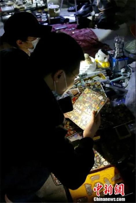 4月2日晚，一位买家在“鬼市”摊位前拿着手电仔细查看货品。<a target='_blank' href='http://www.chinanews.com/'>中新社</a>易海菲 摄