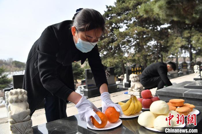 刘利芳代替无法亲赴现场祭拜的客户进行擦墓碑、鞠躬、献花等祭扫仪式并通过手机向客户展示是她的工作之一。　张瑶 摄