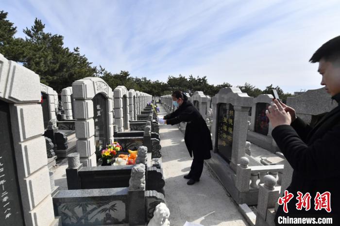 刘利芳代替无法亲赴现场祭拜的客户进行擦墓碑、鞠躬、献花等祭扫仪式并通过手机向客户展示是她的工作之一。　张瑶 摄