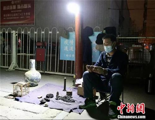 4月2日晚，魏根华在摊位前休息。由于小雨，他已把摊位上的部分货品收起。<a target='_blank' href='http://www.chinanews.com/'>中新社</a>易海菲 摄