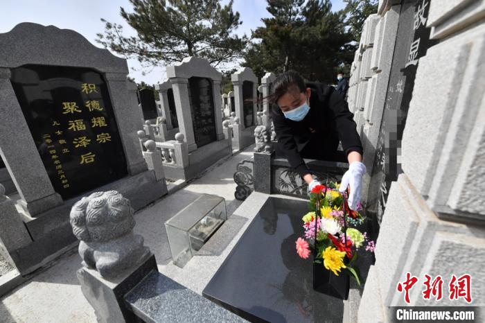 刘利芳代替无法亲赴现场祭拜的客户进行擦墓碑、鞠躬、献花等祭扫仪式并通过手机向客户展示是她的工作之一。　张瑶 摄