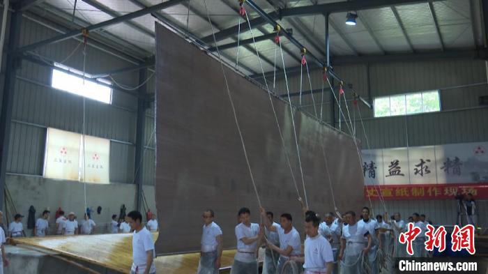 捞纸师傅们将纸帘吊起,送到纸贴区脱帘。 刘鸿鹤 摄