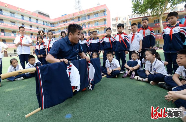 2021年5月11日,在河北省邯郸市邯山区滏河学校,邯郸市红十字中安防减灾服务中心的工作人员向学生们讲解简易担架的制作。